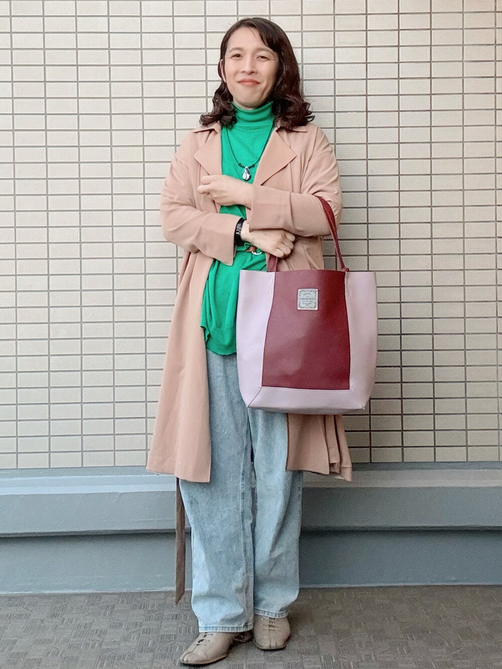 ブルー系のデニムパンツ、ベージュ系のブーツ、グリーン系のニット/セーターを着用したレディースの冬コーディネートの2枚目の写真
