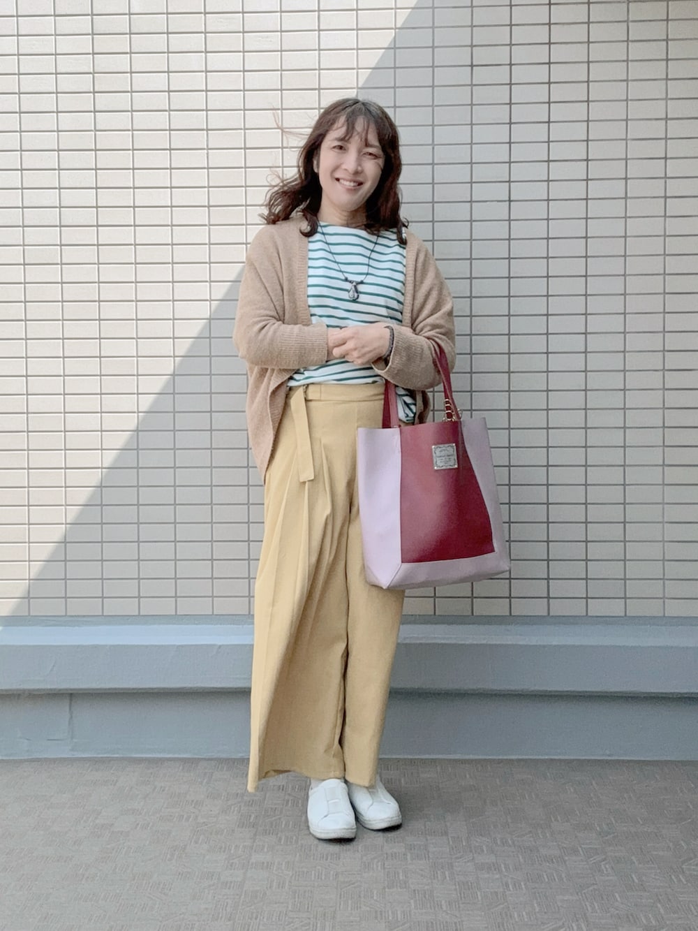 ホワイト系のスニーカー、イエロー系のパンツ、レッド系のトートバッグを着用したレディースの春コーディネートの2枚目の写真