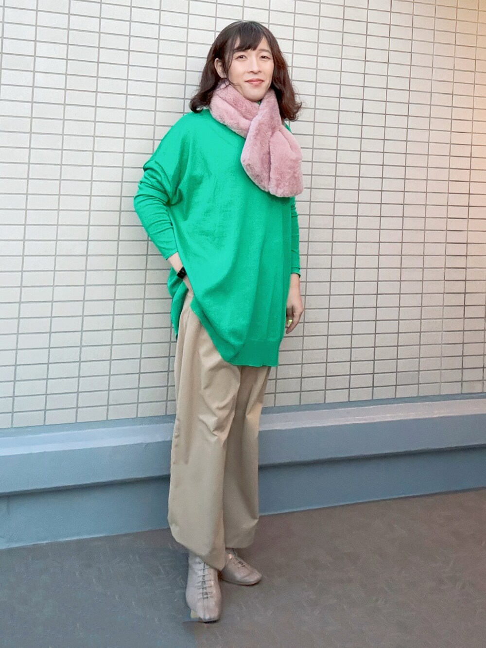 ベージュ系のチノパンツ、ベージュ系のブーツ、グリーン系のニット/セーターを着用したレディースの冬コーディネートの2枚目の写真