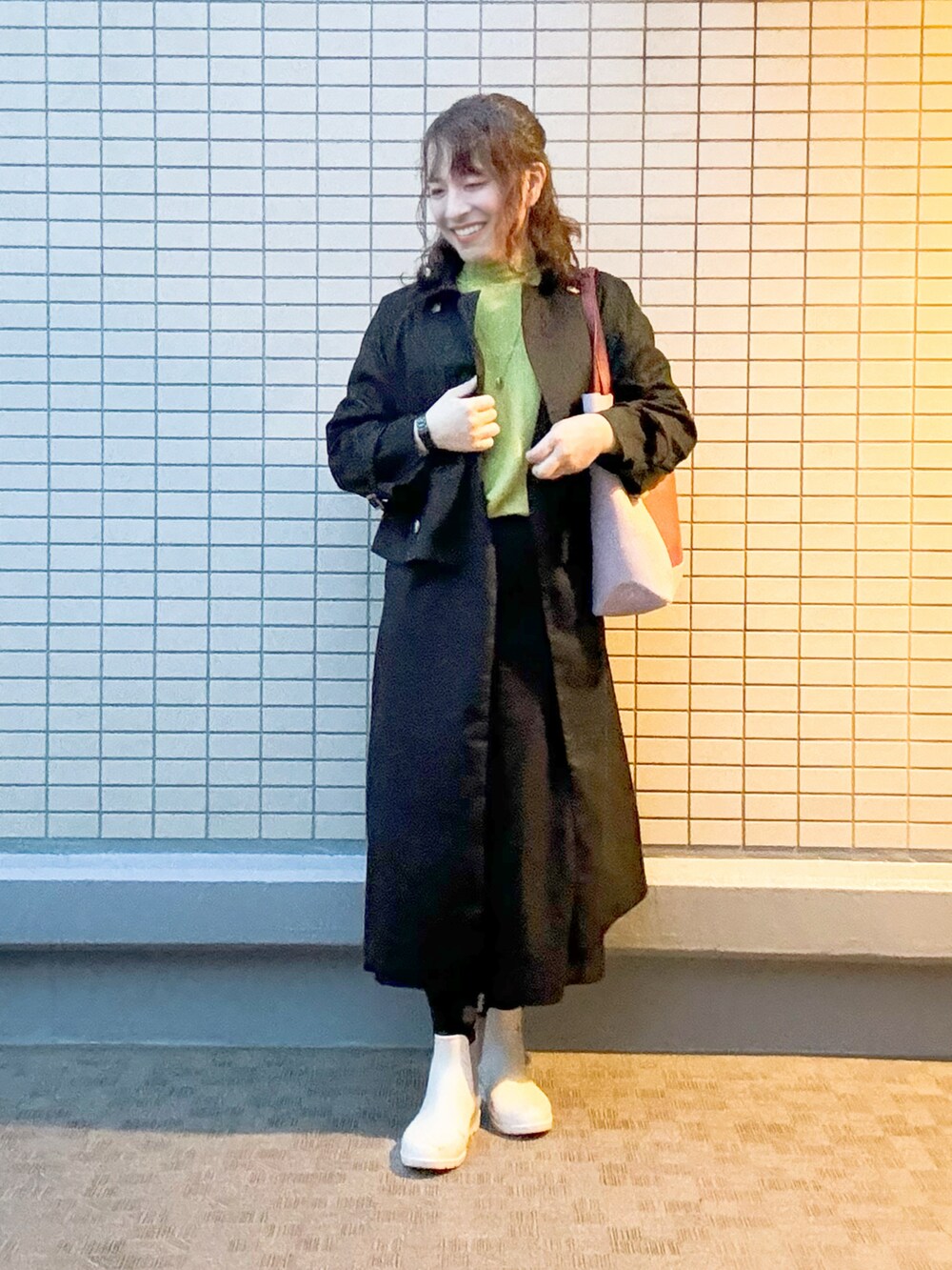 ブラック系のトレンチコート、ブラック系のパンツ、レッド系のトートバッグを着用したレディースの冬コーディネートの3枚目の写真