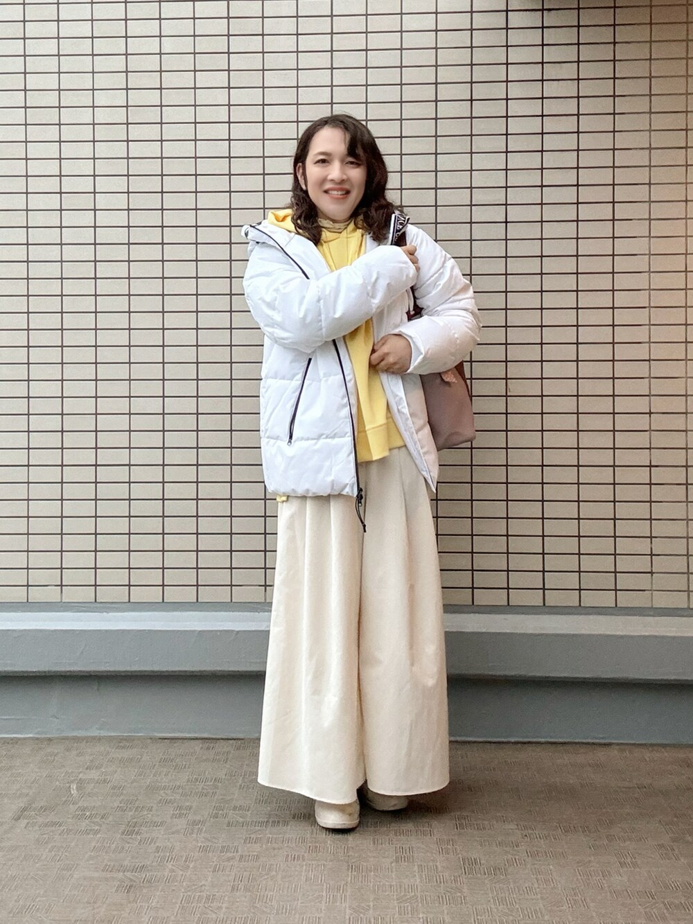 レッド系のトートバッグ、イエロー系のスウェット、ホワイト系のパンツを着用したレディースの冬コーディネートの3枚目の写真