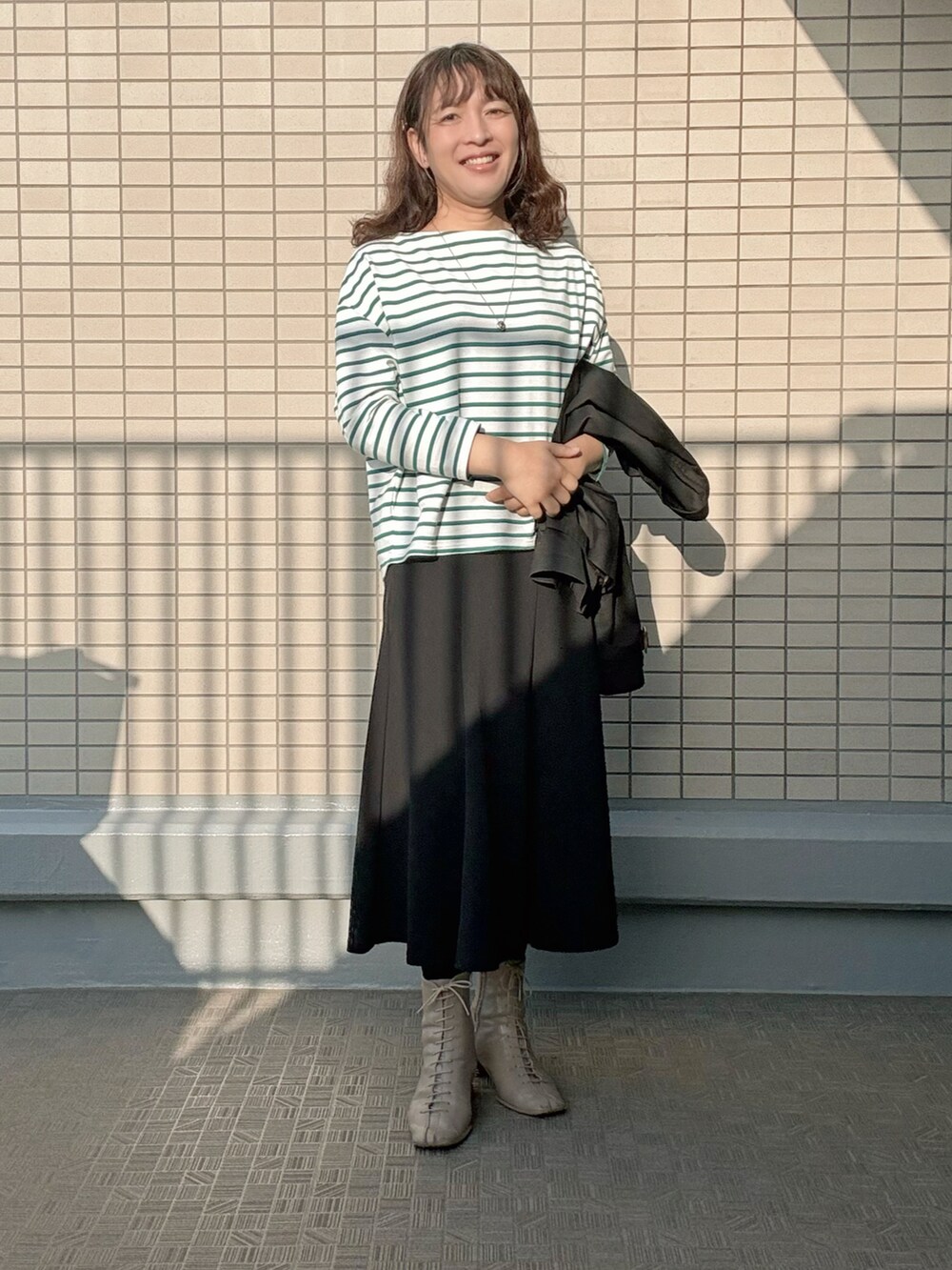 ベージュ系のブーツ、ブラック系のスカート、グリーン系のTシャツ/カットソーを着用したレディースの春コーディネートの3枚目の写真