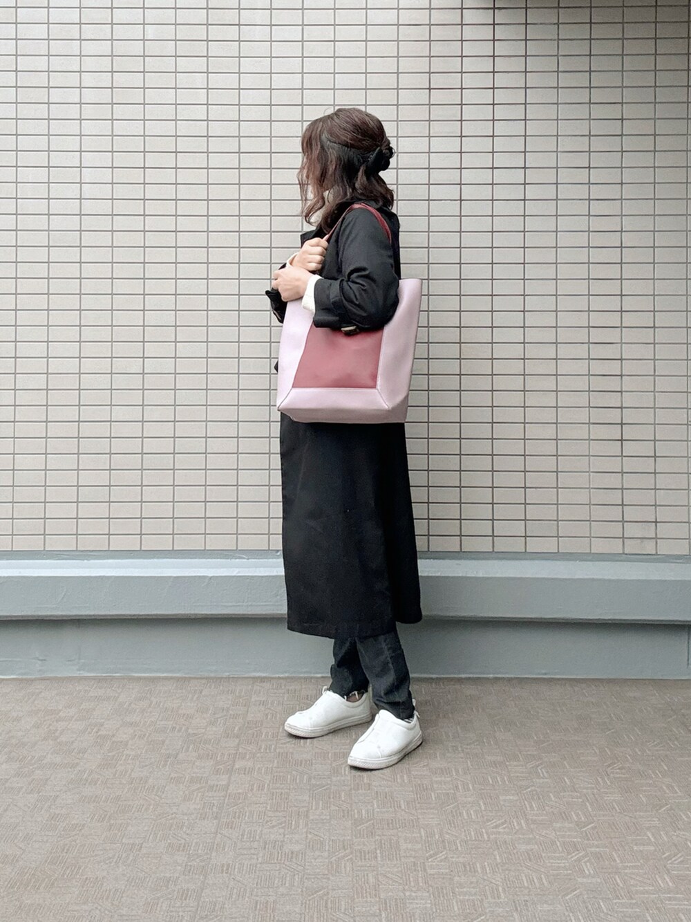 ブラック系のデニムパンツ、ホワイト系のスニーカー、ブラック系のトレンチコートを着用したレディースの春コーディネートの2枚目の写真