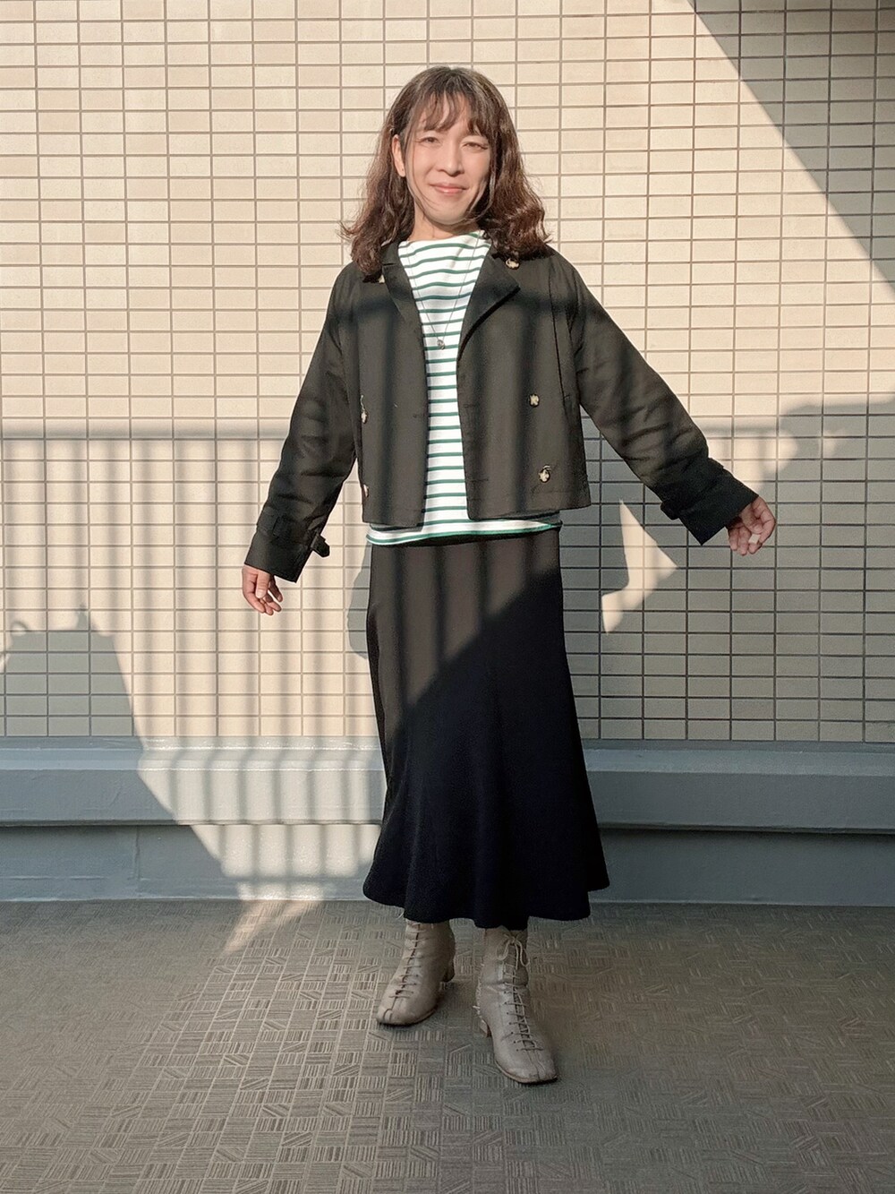 ベージュ系のブーツ、ブラック系のスカート、グリーン系のTシャツ/カットソーを着用したレディースの春コーディネートの4枚目の写真