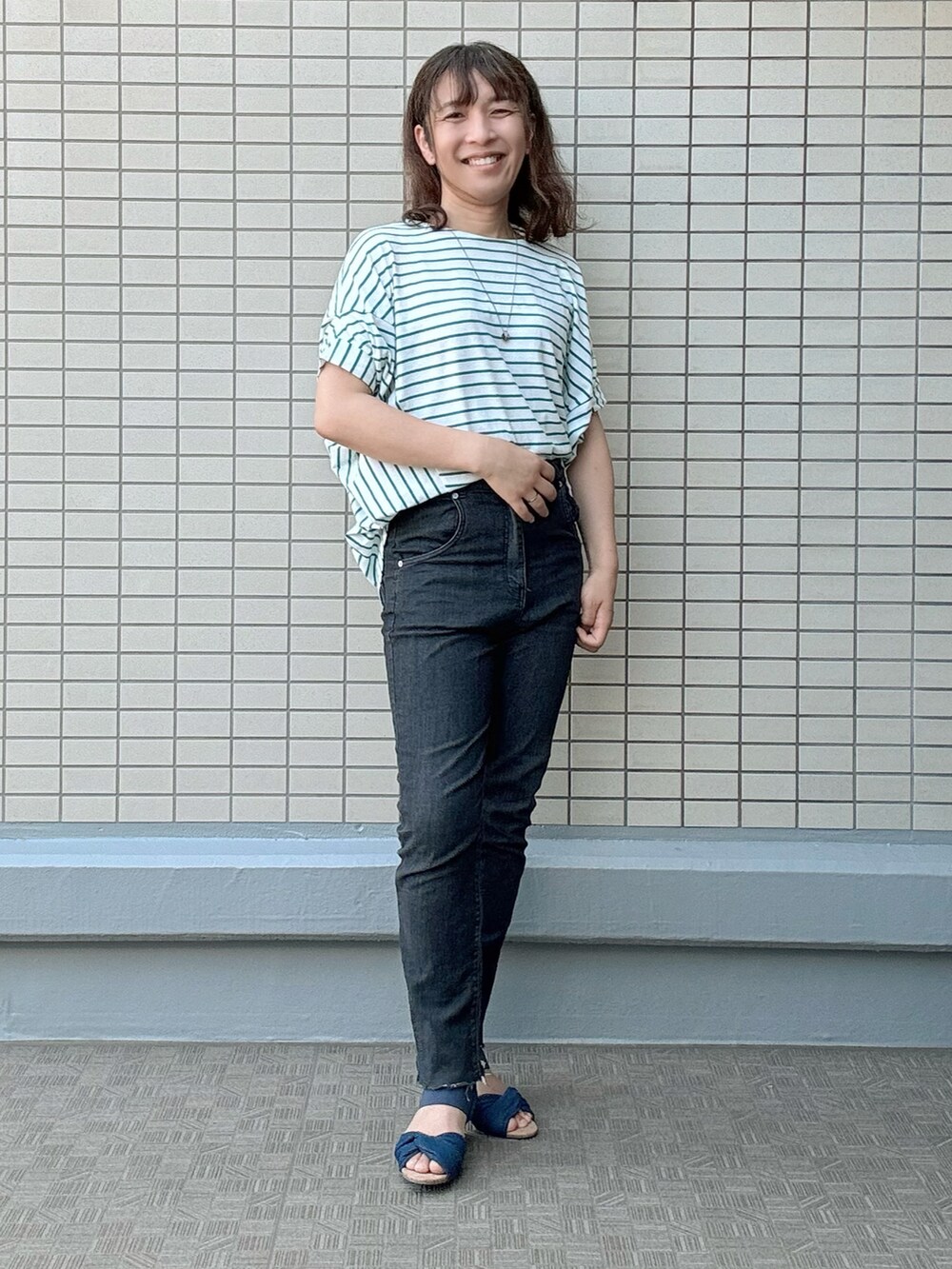 ブルー系のサンダル、ブラック系のデニムパンツ、その他のTシャツ/カットソーを着用したレディースの夏コーディネートの4枚目の写真