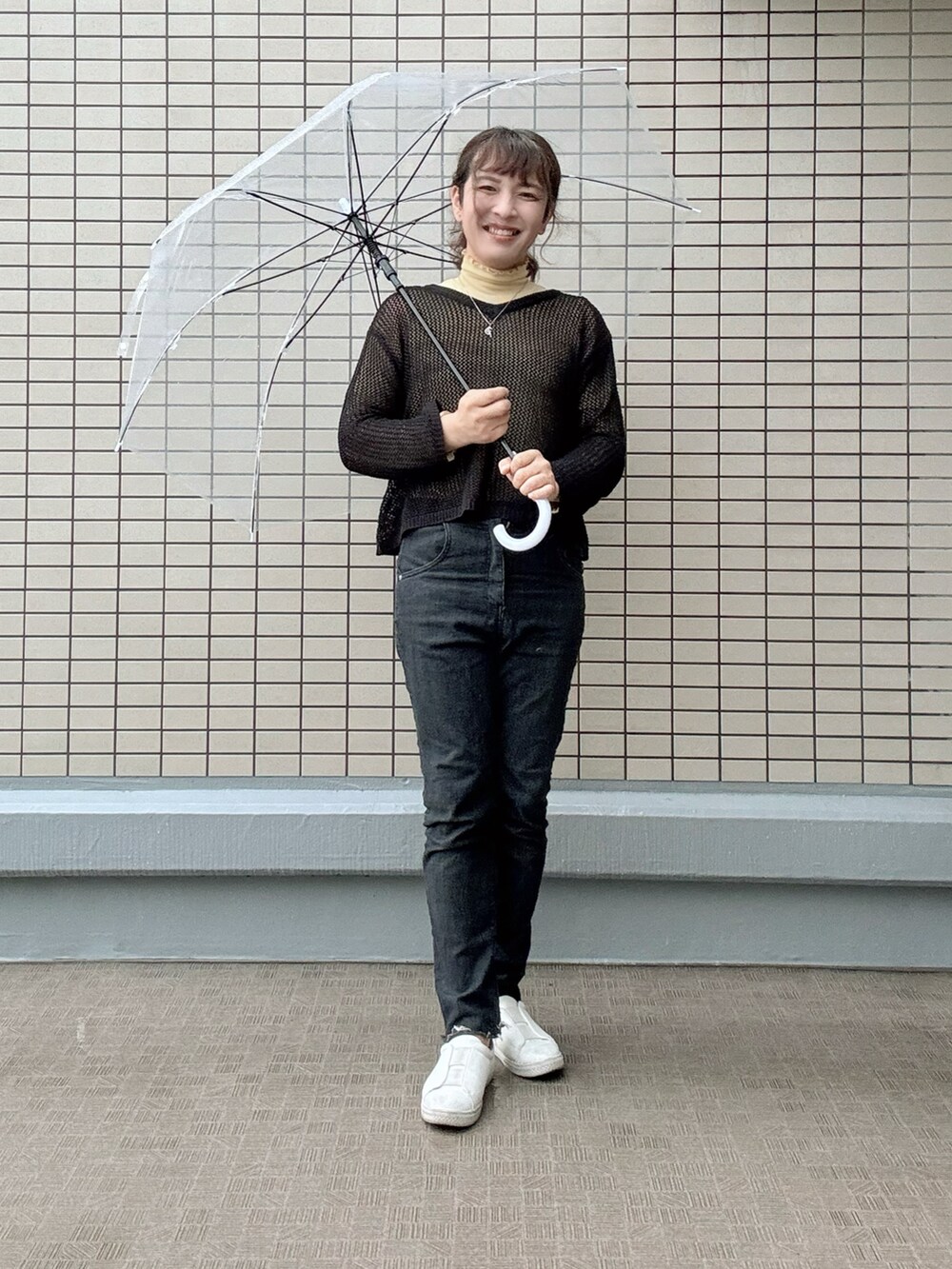 ホワイト系のスニーカー、ブラック系のデニムパンツ、ブラック系のトレンチコートを着用したレディースの春コーディネートの2枚目の写真