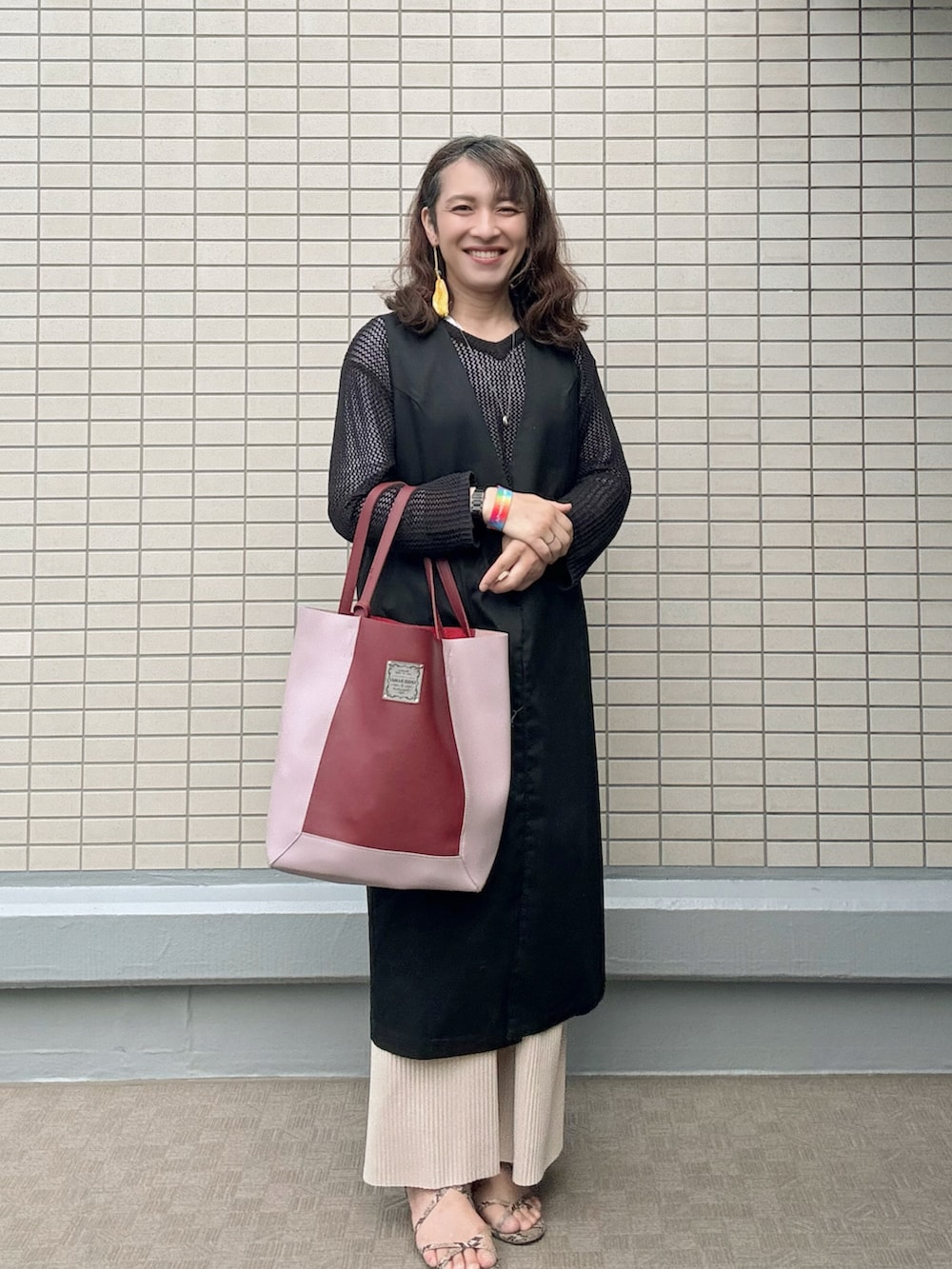その他のサンダル、レッド系のトートバッグ、ブラック系のトレンチコートを着用したレディースの春コーディネートの2枚目の写真