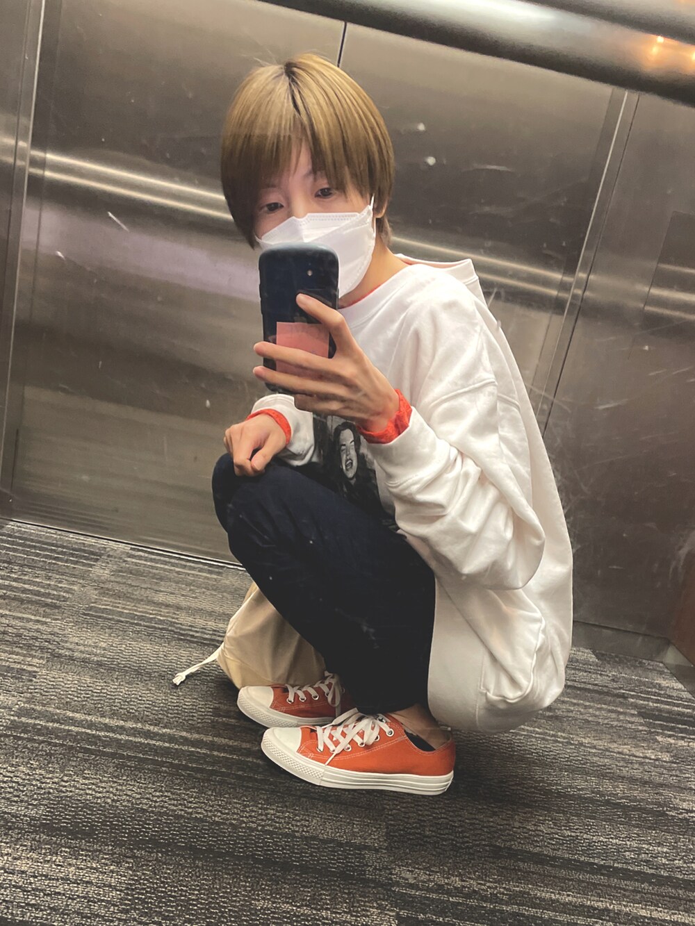 ホワイト系のスウェット、オレンジ系のTシャツ/カットソー、ブルー系のデニムパンツを着用したレディースの春コーディネートの2枚目の写真