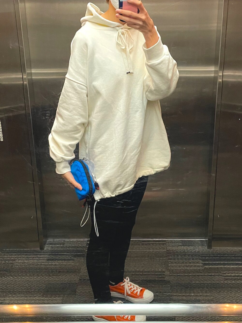 ホワイト系のパーカー、ブラック系のその他パンツ、オレンジ系のスニーカーを着用したレディースの春コーディネートの2枚目の写真