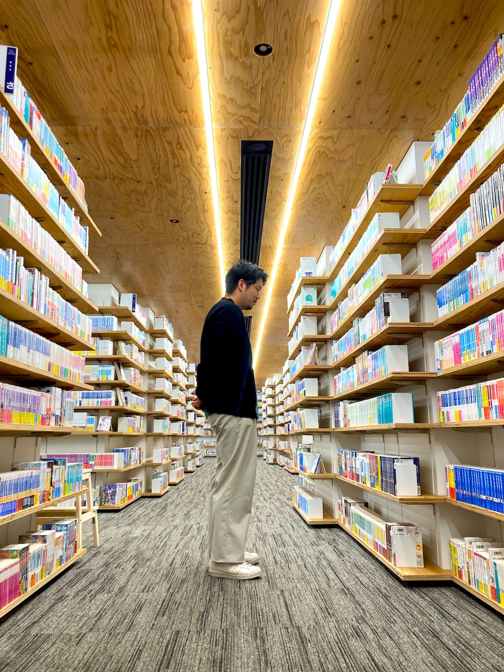 グリーン系のTシャツ/カットソー、ホワイト系のスニーカー、ブラック系のカーディガン/ボレロを着用したメンズの秋コーディネートの2枚目の写真