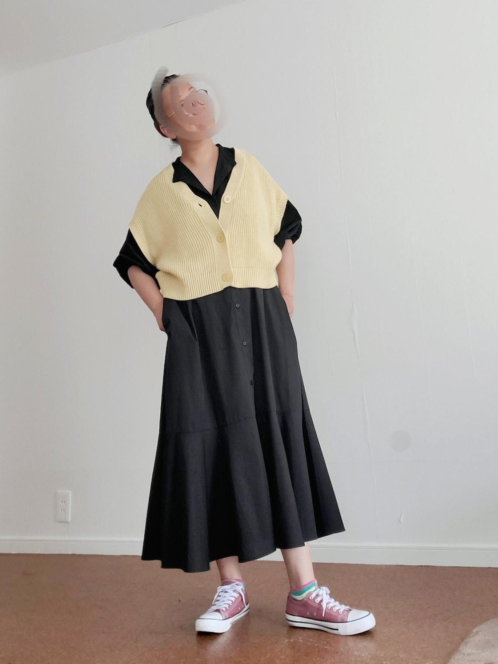 ピンク系のスニーカー、イエロー系のベスト、ブラック系のワンピースを着用したレディースの春コーディネートの2枚目の写真