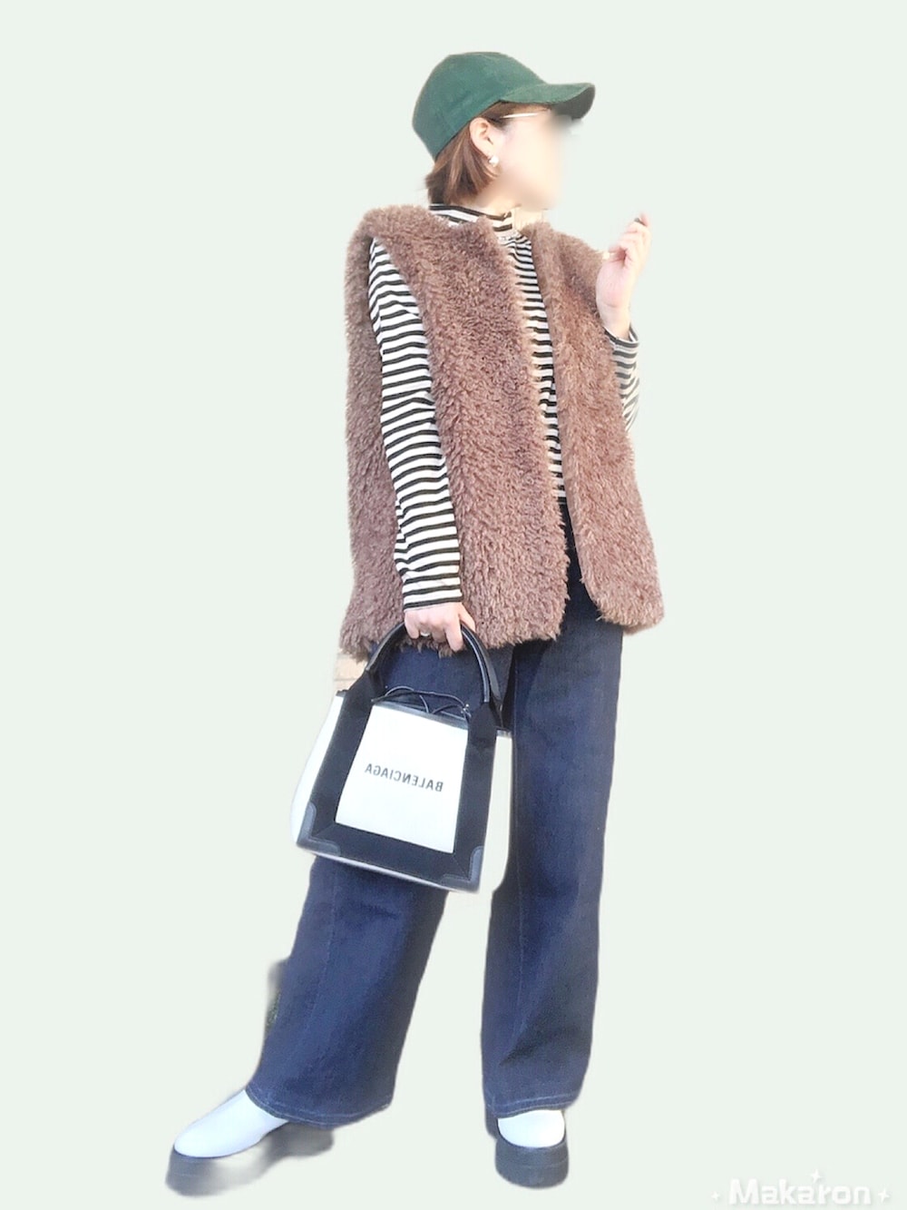 ブラウン系のベスト、ブルー系のデニムパンツ、ホワイト系のトートバッグを着用したレディースの秋コーディネートの2枚目の写真