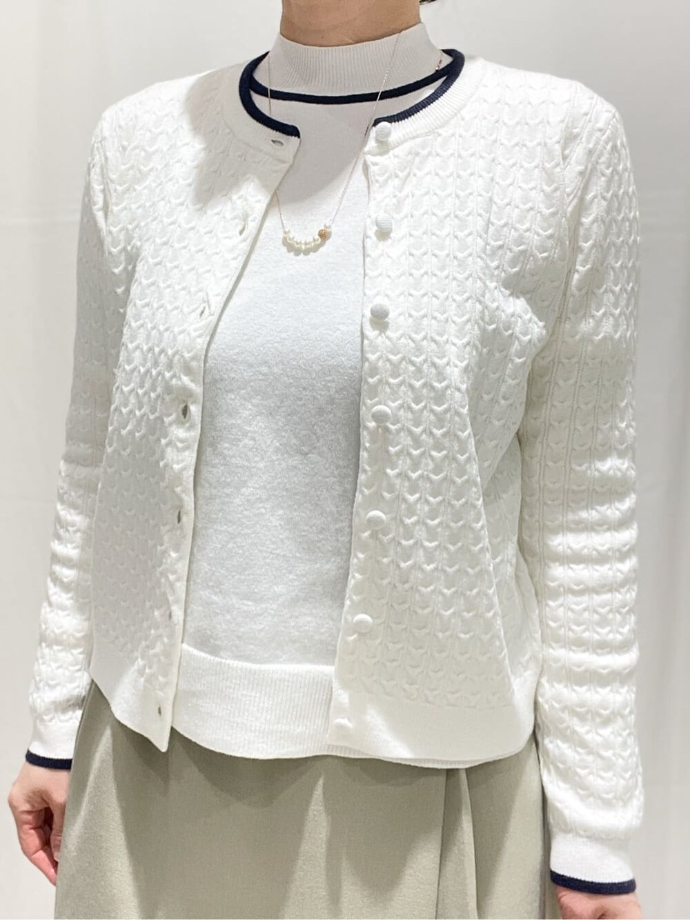 ホワイト系のカーディガン/ボレロ、ホワイト系のニット/セーター、ベージュ系のスカートを着用したレディースの冬コーディネートの4枚目の写真