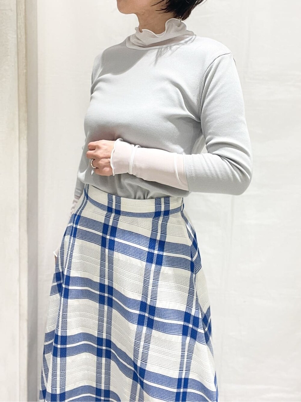 ホワイト系のカーディガン/ボレロ、グレー系のTシャツ/カットソー、ブルー系のスカートを着用したレディースの冬コーディネートの6枚目の写真