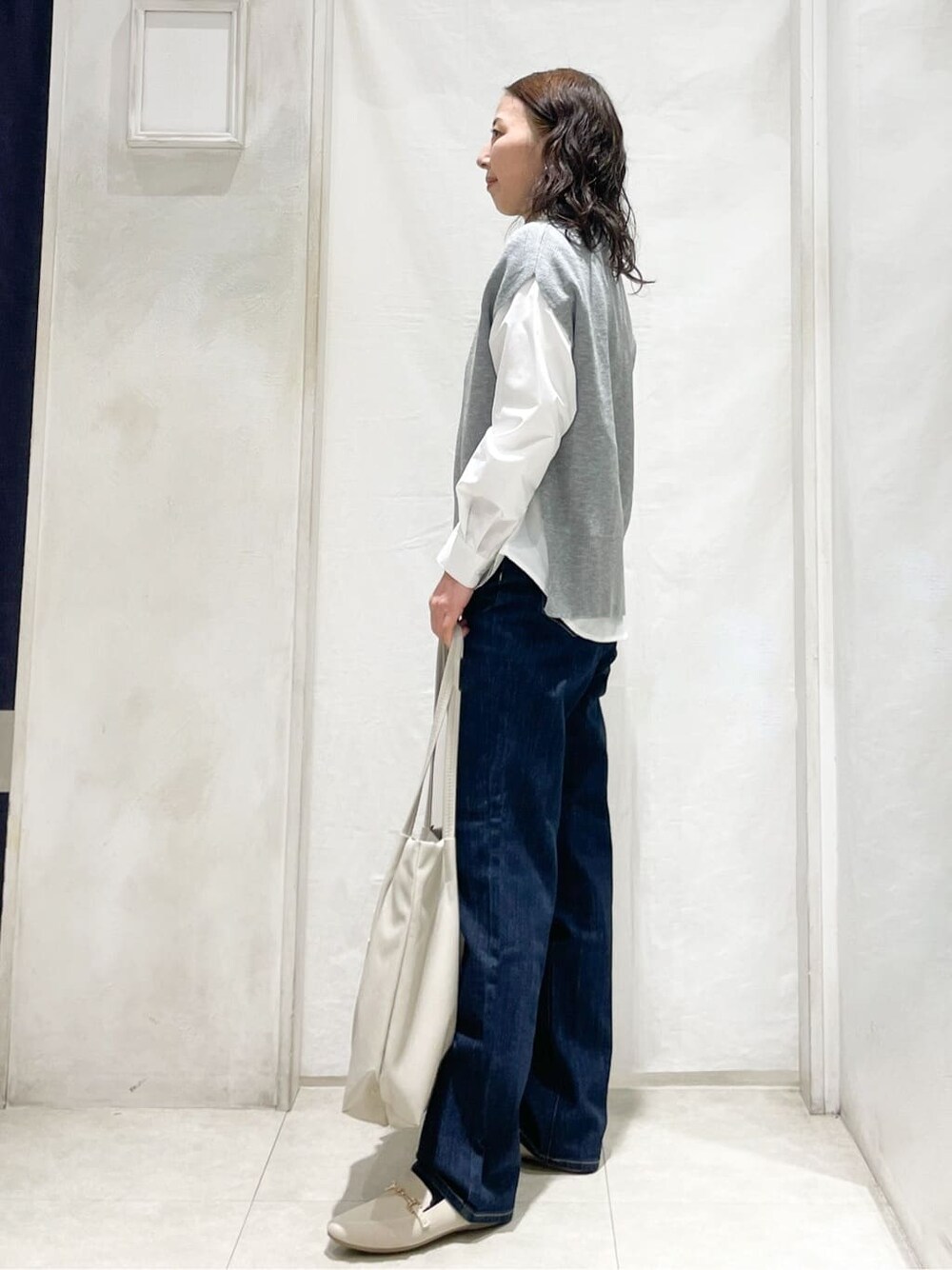 グレー系のシャツ/ブラウス、ブルー系のデニムパンツ、ベージュ系のトートバッグを着用したレディースの冬コーディネートの2枚目の写真
