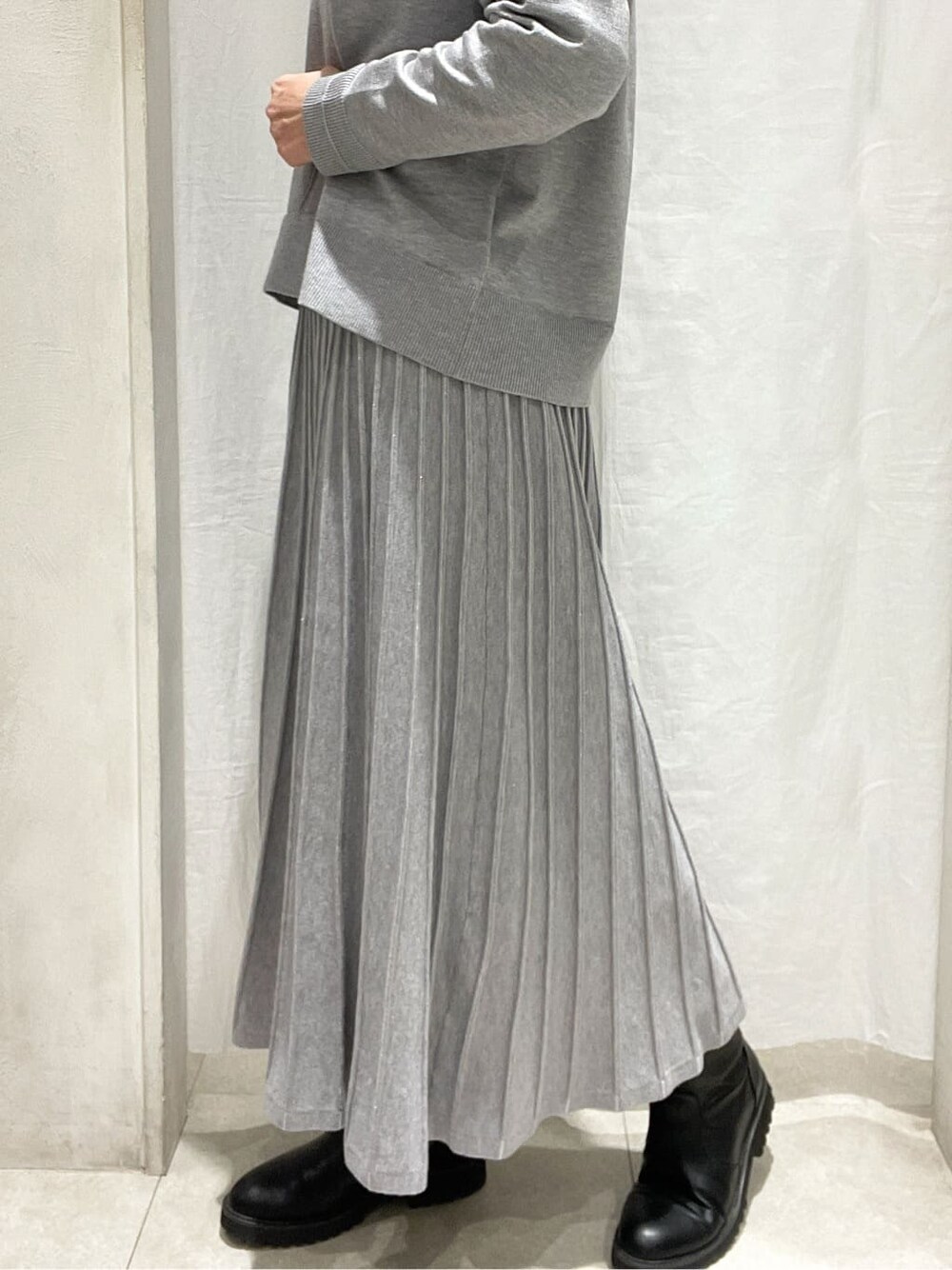 ブルー系のノーカラーコート、グレー系のニット/セーター、グレー系のスカートを着用したレディースの冬コーディネートの8枚目の写真