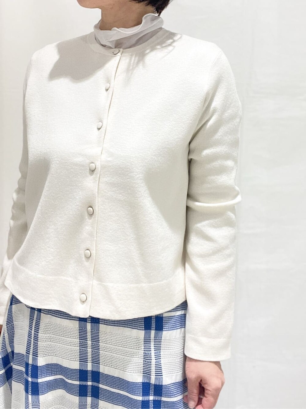 ホワイト系のカーディガン/ボレロ、グレー系のTシャツ/カットソー、ブルー系のスカートを着用したレディースの冬コーディネートの5枚目の写真
