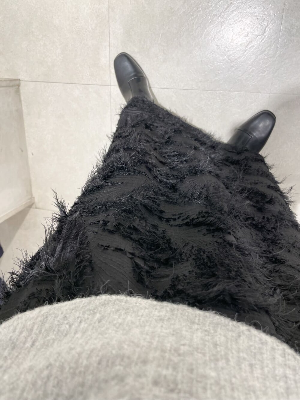 グレー系のニット/セーター、ブラック系のスカート、シルバー系のイヤリングを着用したレディースの冬コーディネートの6枚目の写真