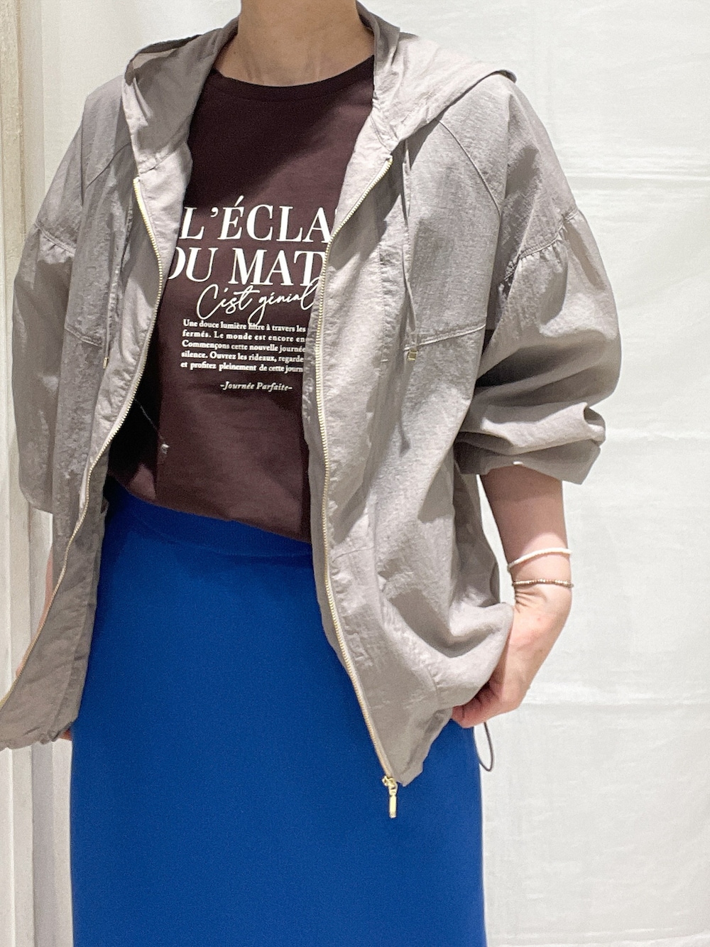 ベージュ系のブルゾン、ブラウン系のTシャツ/カットソー、ブルー系のスカートを着用したレディースの春コーディネートの4枚目の写真