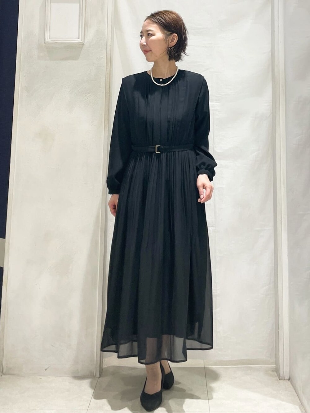 ブルー系のノーカラージャケット、ブラック系のワンピース、ベージュ系のショルダーバッグを着用したレディースの冬コーディネートの4枚目の写真