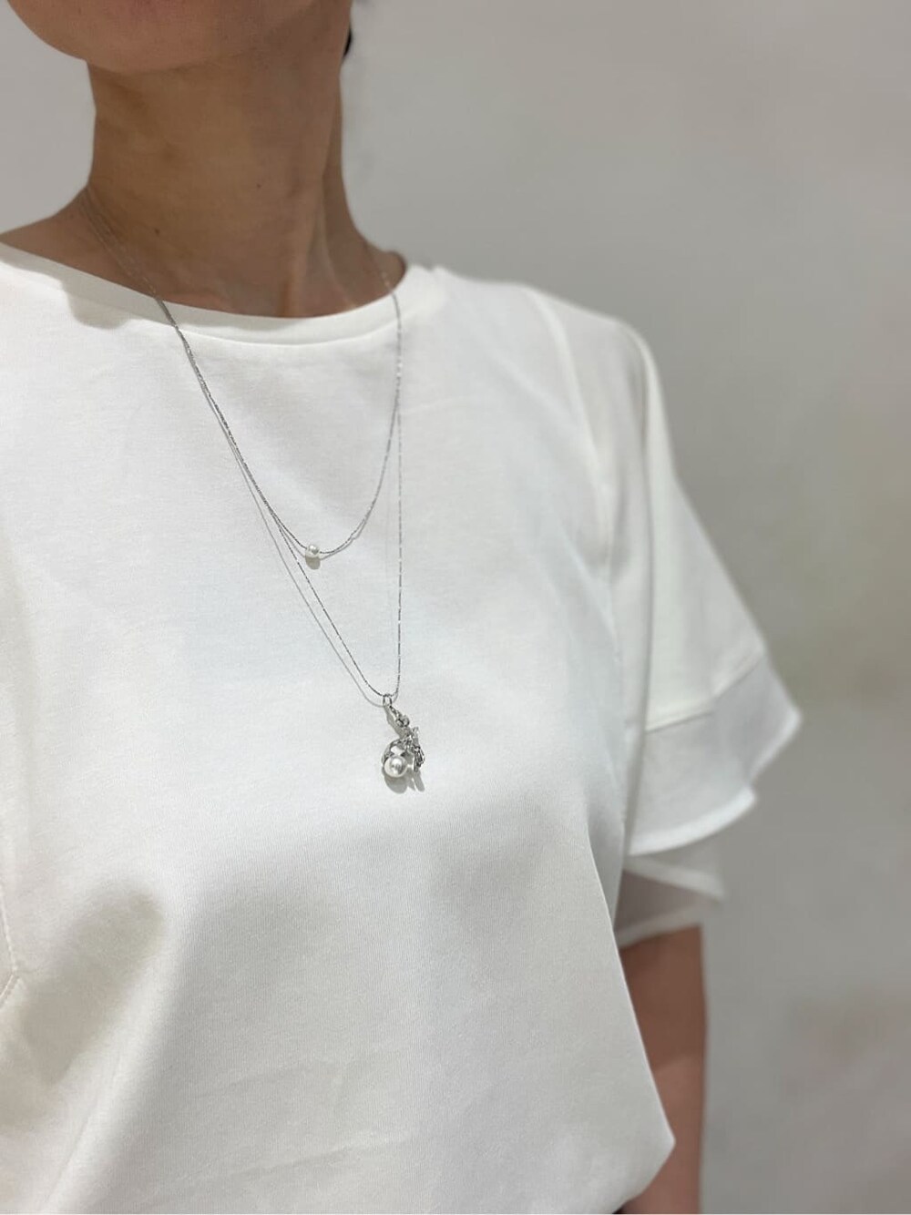 ホワイト系のTシャツ/カットソー、ブラック系のトートバッグ、グレー系のイヤリングを着用したレディースの夏コーディネートの4枚目の写真