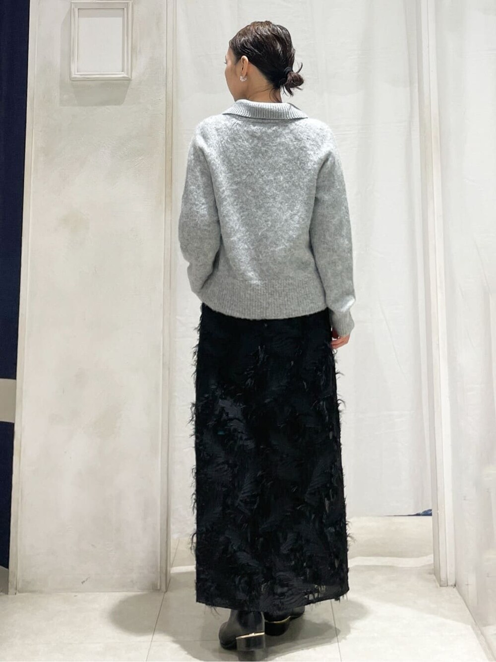 グレー系のニット/セーター、ブラック系のスカート、シルバー系のイヤリングを着用したレディースの冬コーディネートの4枚目の写真