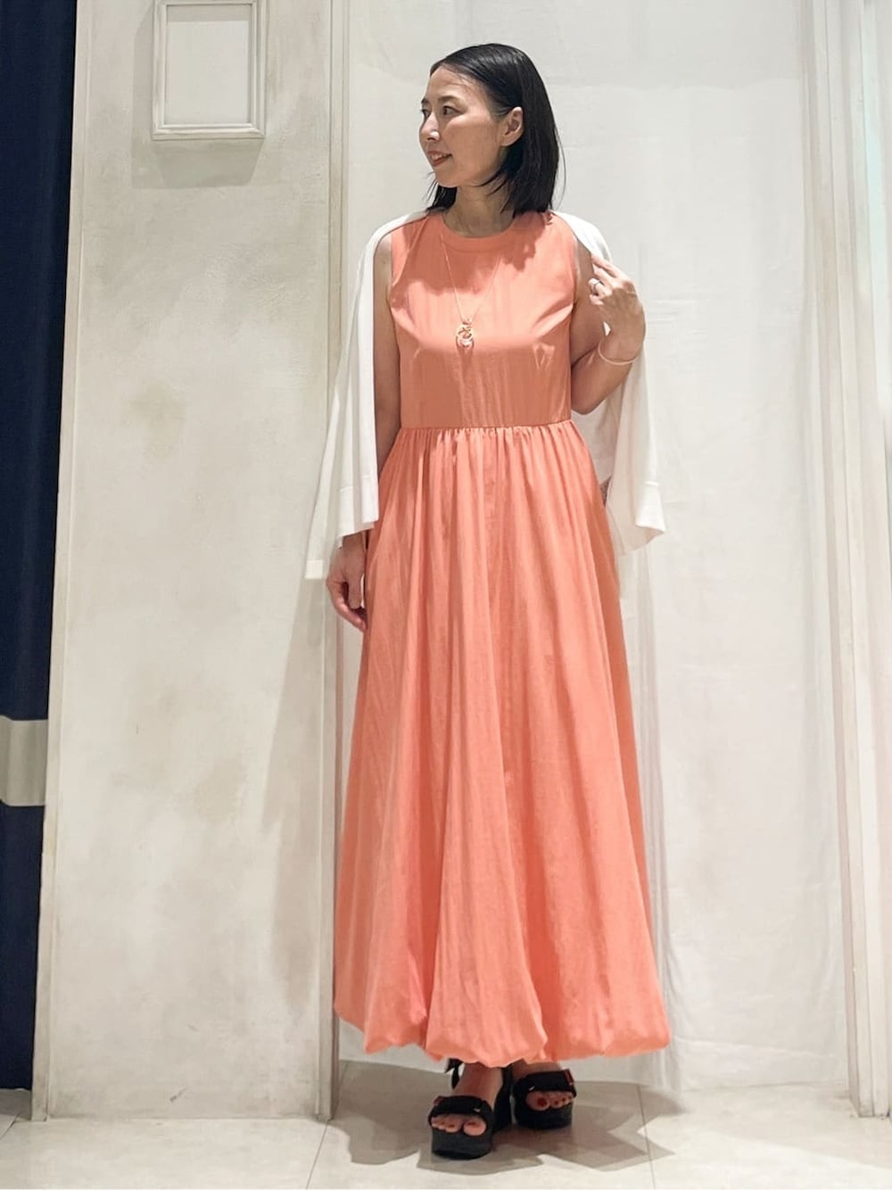 ホワイト系のカーディガン/ボレロ、オレンジ系のワンピース、その他のネックレスを着用したレディースの夏コーディネートの2枚目の写真