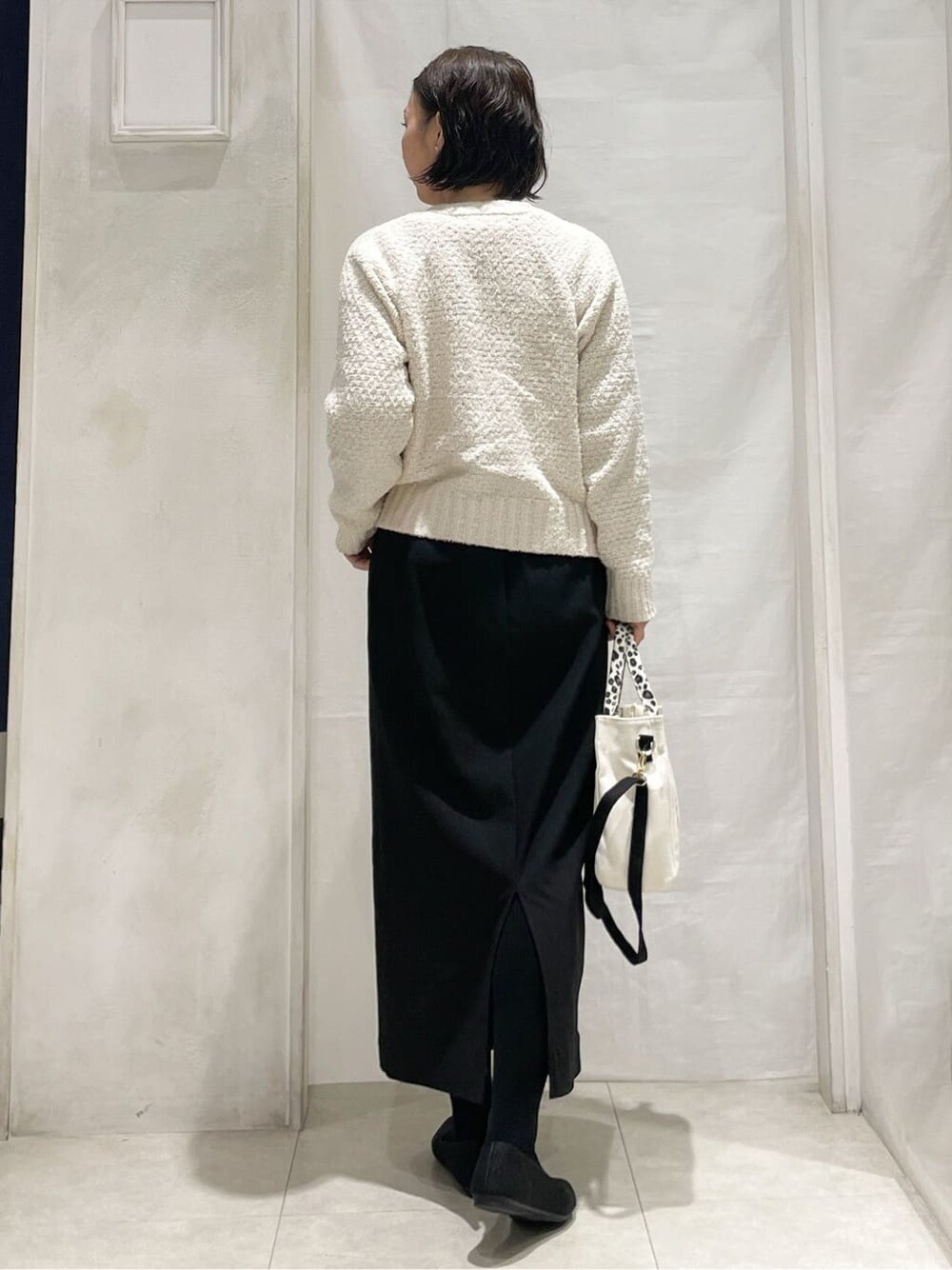 ホワイト系のカーディガン/ボレロ、ホワイト系のTシャツ/カットソー、ブラック系のスカートを着用したレディースの春コーディネートの3枚目の写真