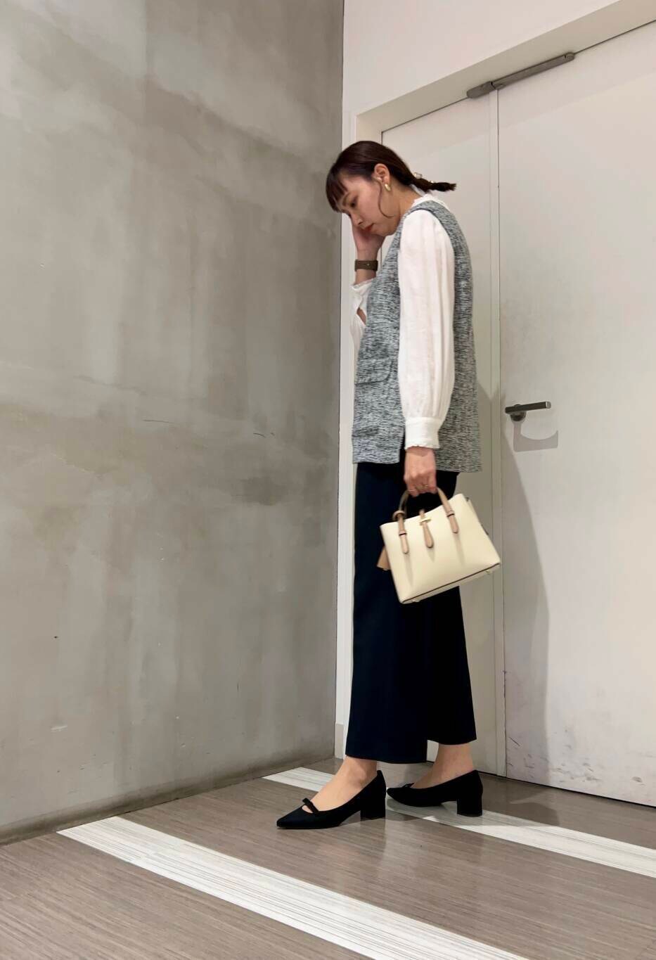 ホワイト系のハンドバッグ、ホワイト系のシャツ/ブラウス、ブラック系のパンプスを着用したレディースの冬コーディネートの3枚目の写真
