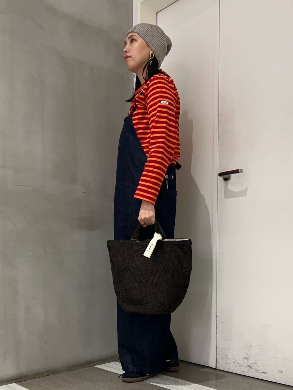 ブルー系のサロペット/オーバーオール、ブラック系のスニーカー、レッド系のTシャツ/カットソーを着用したレディースの秋コーディネートの2枚目の写真