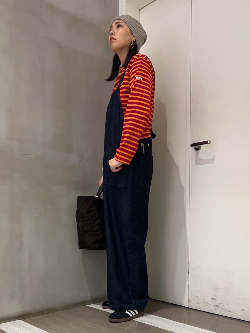 ブルー系のサロペット/オーバーオール、ブラック系のスニーカー、レッド系のTシャツ/カットソーを着用したレディースの秋コーディネートの4枚目の写真