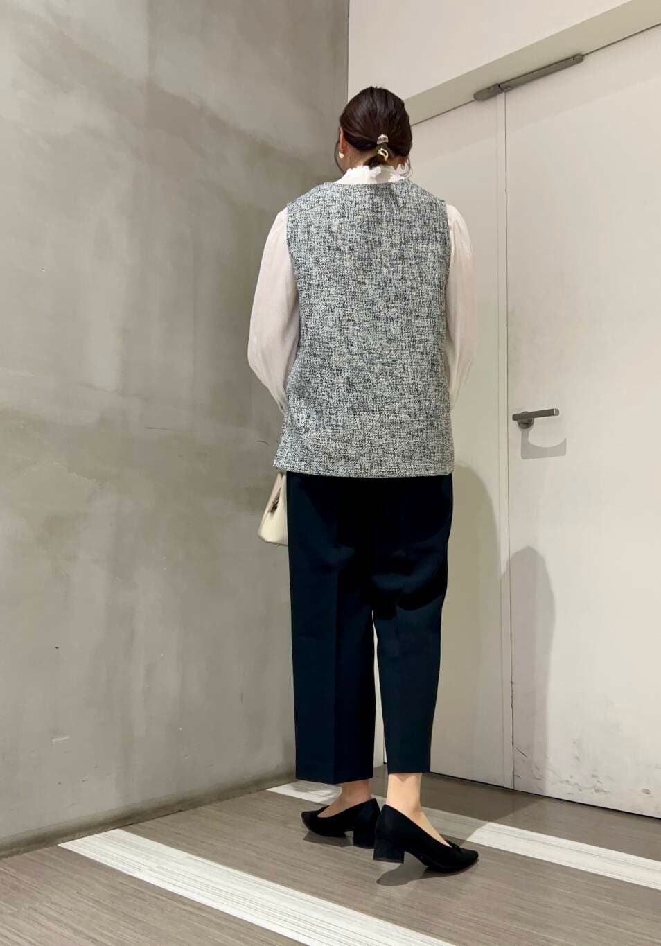 ホワイト系のハンドバッグ、ホワイト系のシャツ/ブラウス、ブラック系のパンプスを着用したレディースの冬コーディネートの4枚目の写真