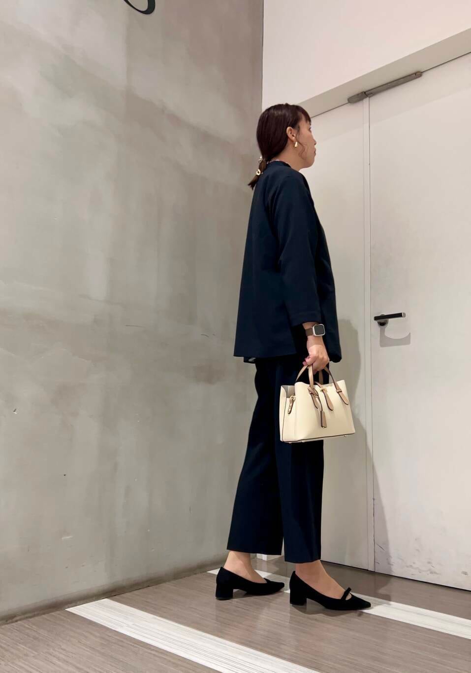 ホワイト系のハンドバッグ、ホワイト系のシャツ/ブラウス、ブラック系のパンプスを着用したレディースの冬コーディネートの6枚目の写真