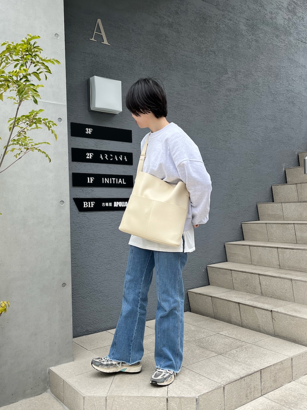 ホワイト系のショルダーバッグ、グレー系のスニーカー、ブルー系のデニムパンツを着用したレディースの春コーディネートの2枚目の写真