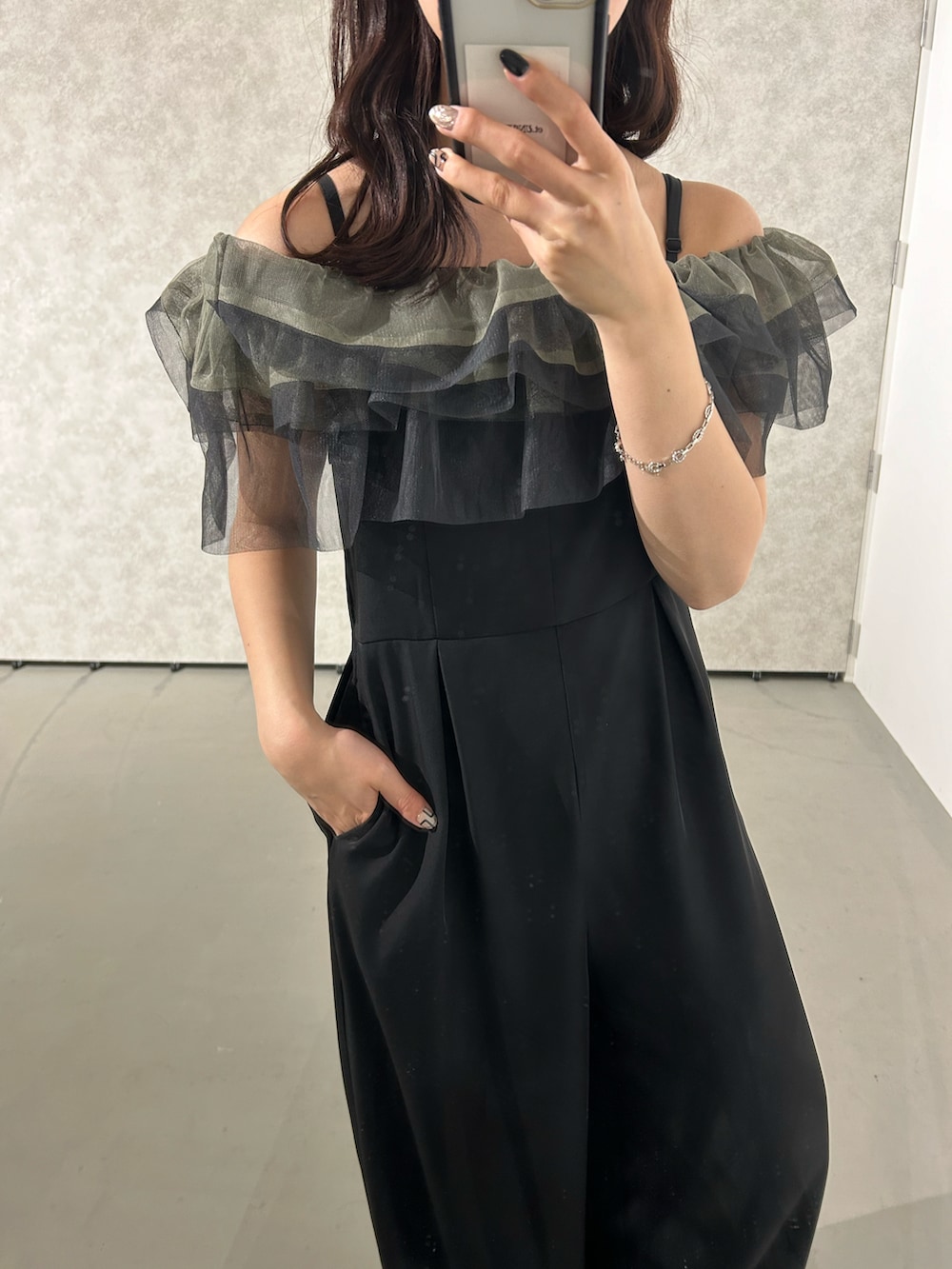 ブラック系のパンツドレス、ゴールド系のネックレス、ゴールド系のピアス（両耳用）を着用したレディースの春コーディネートの5枚目の写真