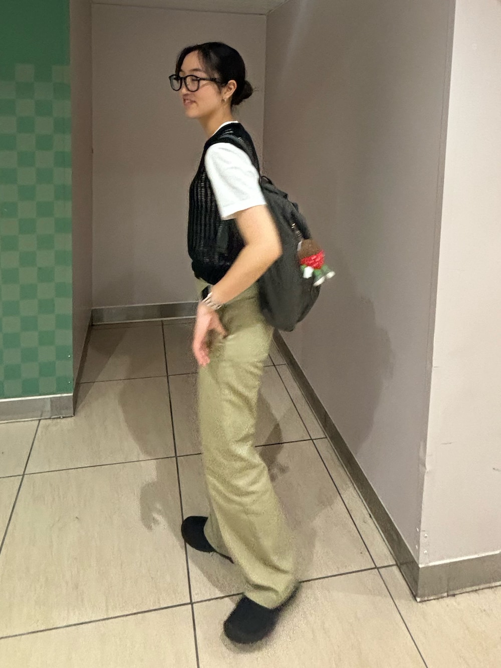 ブラウン系のチノパンツ、ブラック系のベスト、グレー系のバックパック/リュックを着用したレディースの夏コーディネートの3枚目の写真