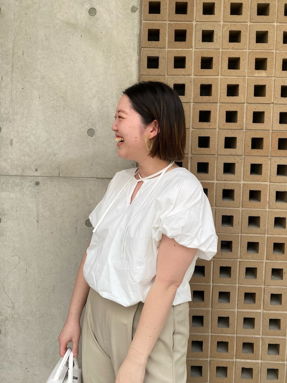 ホワイト系のシャツ/ブラウス、ベージュ系のパンツ、ホワイト系のショルダーバッグを着用したレディースの春コーディネートの2枚目の写真