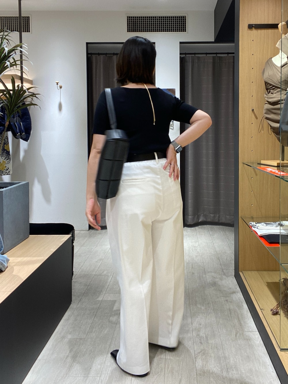 ブラック系のニット/セーター、ブラック系のショルダーバッグ、ホワイト系のその他パンツを着用したレディースの夏コーディネートの7枚目の写真