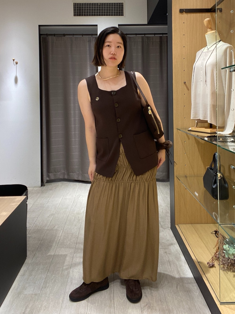 ブラウン系のニット/セーター、ブラウン系のショルダーバッグ、ブラウン系のスニーカーを着用したレディースの秋コーディネートの2枚目の写真