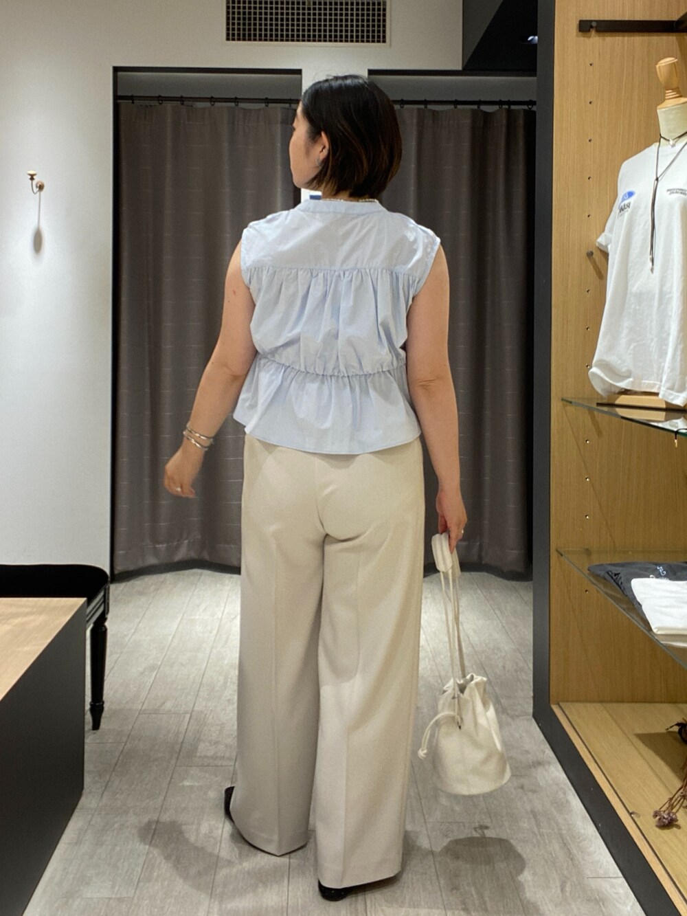ブルー系のシャツ/ブラウス、ブラック系のパンプス、ホワイト系のショルダーバッグを着用したレディースの夏コーディネートの6枚目の写真