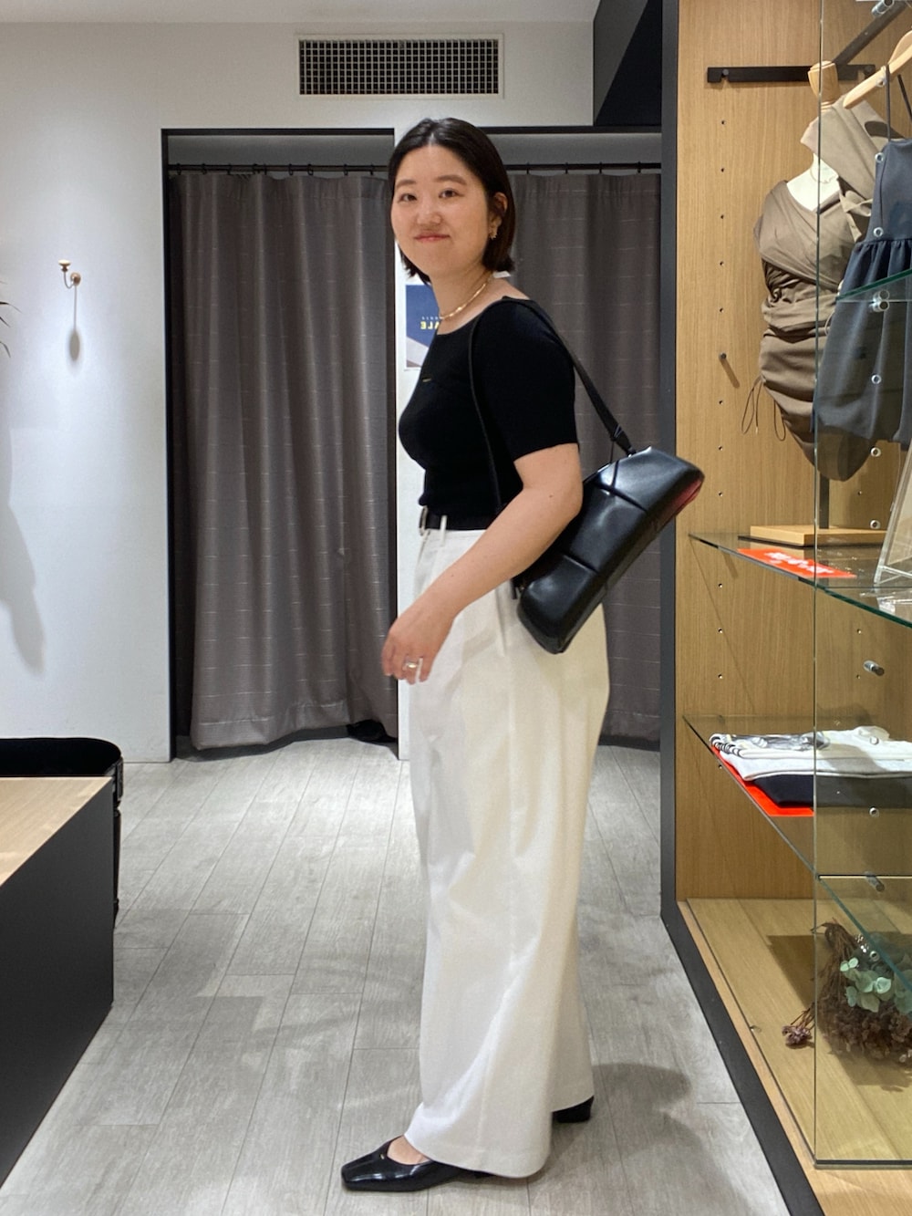 ブラック系のニット/セーター、ブラック系のショルダーバッグ、ホワイト系のその他パンツを着用したレディースの夏コーディネートの5枚目の写真