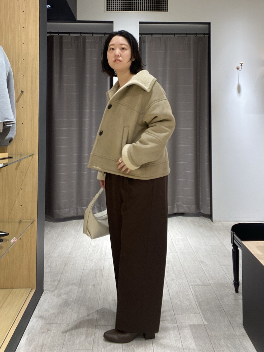 ベージュ系のその他アウター、ホワイト系のニット/セーター、ホワイト系のショルダーバッグを着用したレディースの秋コーディネートの4枚目の写真