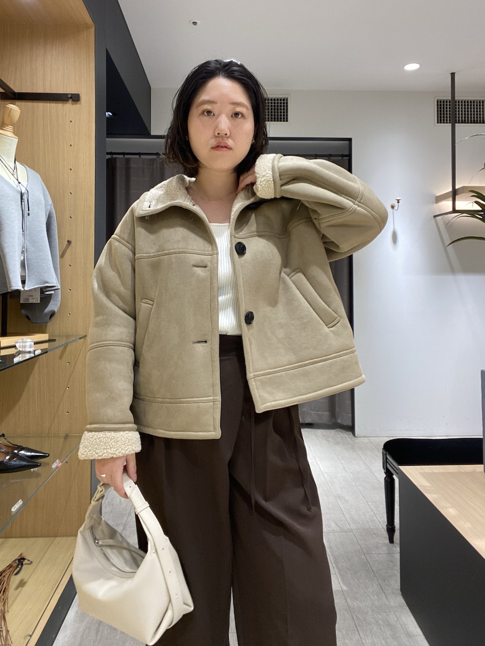 ベージュ系のその他アウター、ホワイト系のニット/セーター、ホワイト系のショルダーバッグを着用したレディースの秋コーディネートの2枚目の写真