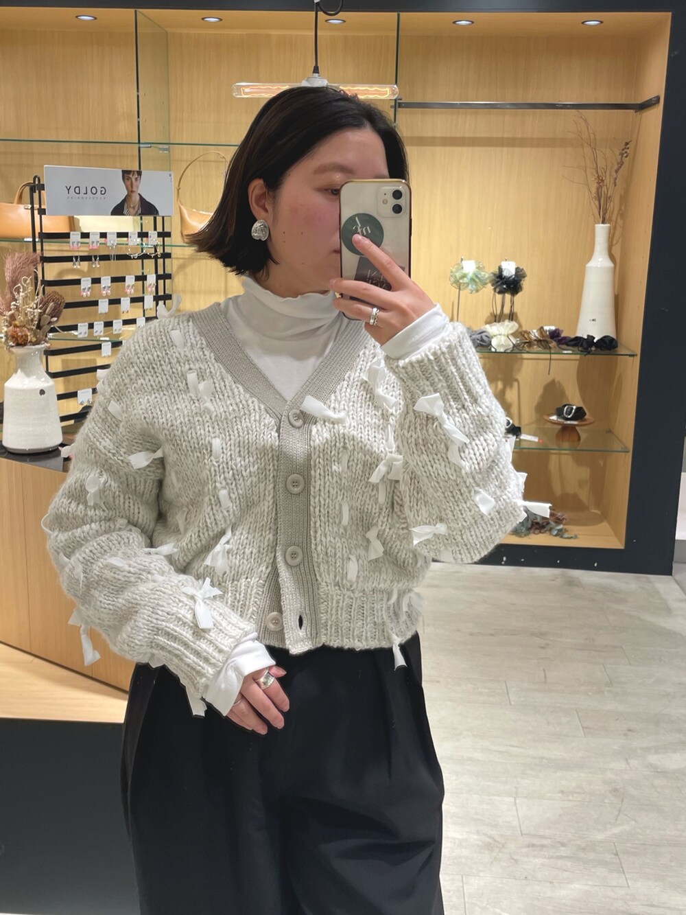 ブラック系のブーツ、ブラック系のその他パンツ、ホワイト系のカーディガン/ボレロを着用したレディースの冬コーディネートの2枚目の写真