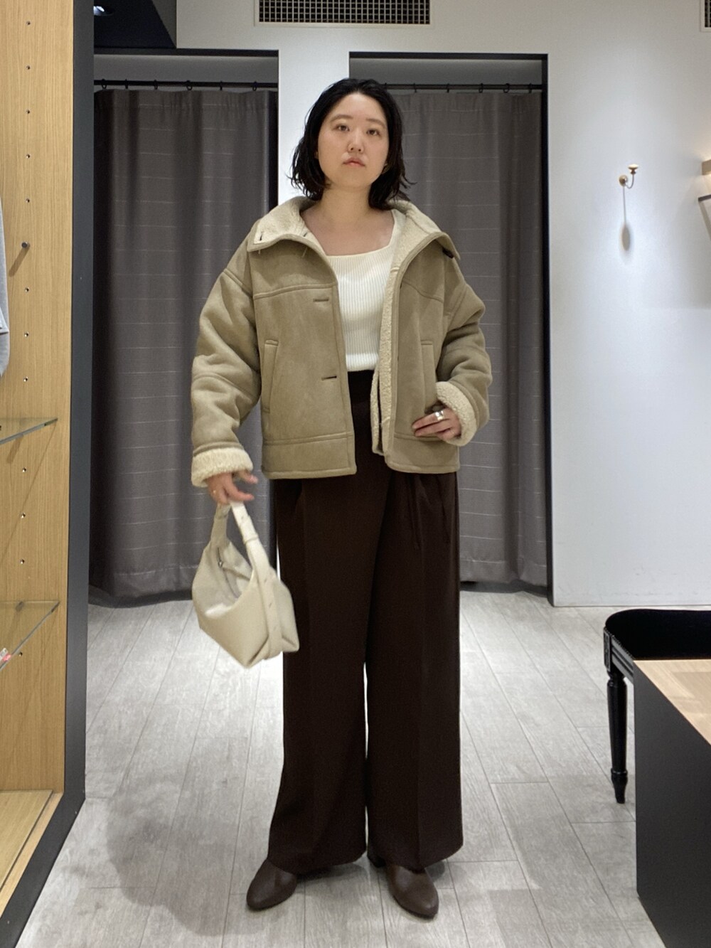 ベージュ系のその他アウター、ホワイト系のニット/セーター、ホワイト系のショルダーバッグを着用したレディースの秋コーディネートの6枚目の写真