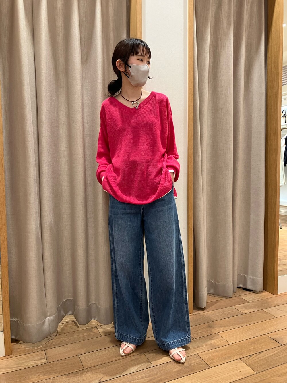 ブルー系のデニムパンツ、ピンク系のニット/セーター、ホワイト系のサンダルを着用したレディースの春コーディネートの2枚目の写真