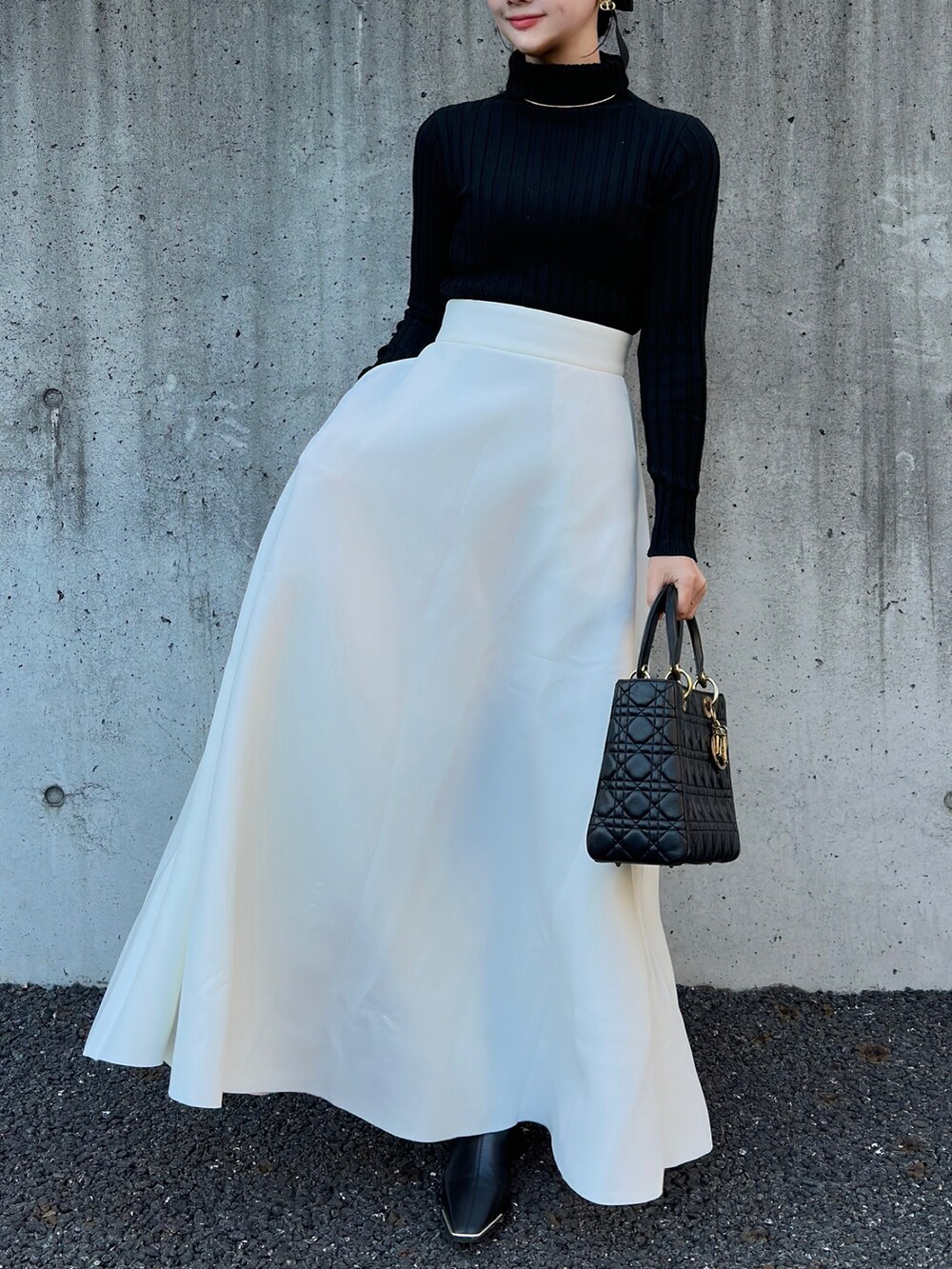 ブラック系のハンドバッグ、ホワイト系のスカート、ブラック系のTシャツ/カットソーを着用したレディースの冬コーディネートの2枚目の写真