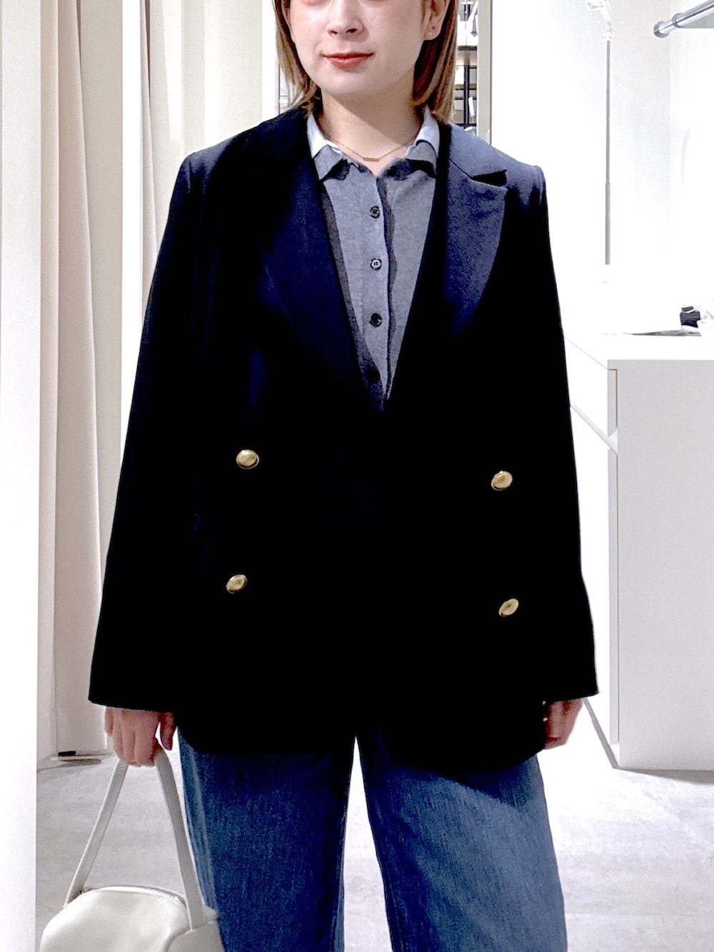 ホワイト系のハンドバッグ、ブルー系のテーラードジャケット、グレー系のニット/セーターを着用したレディースの春コーディネートの6枚目の写真