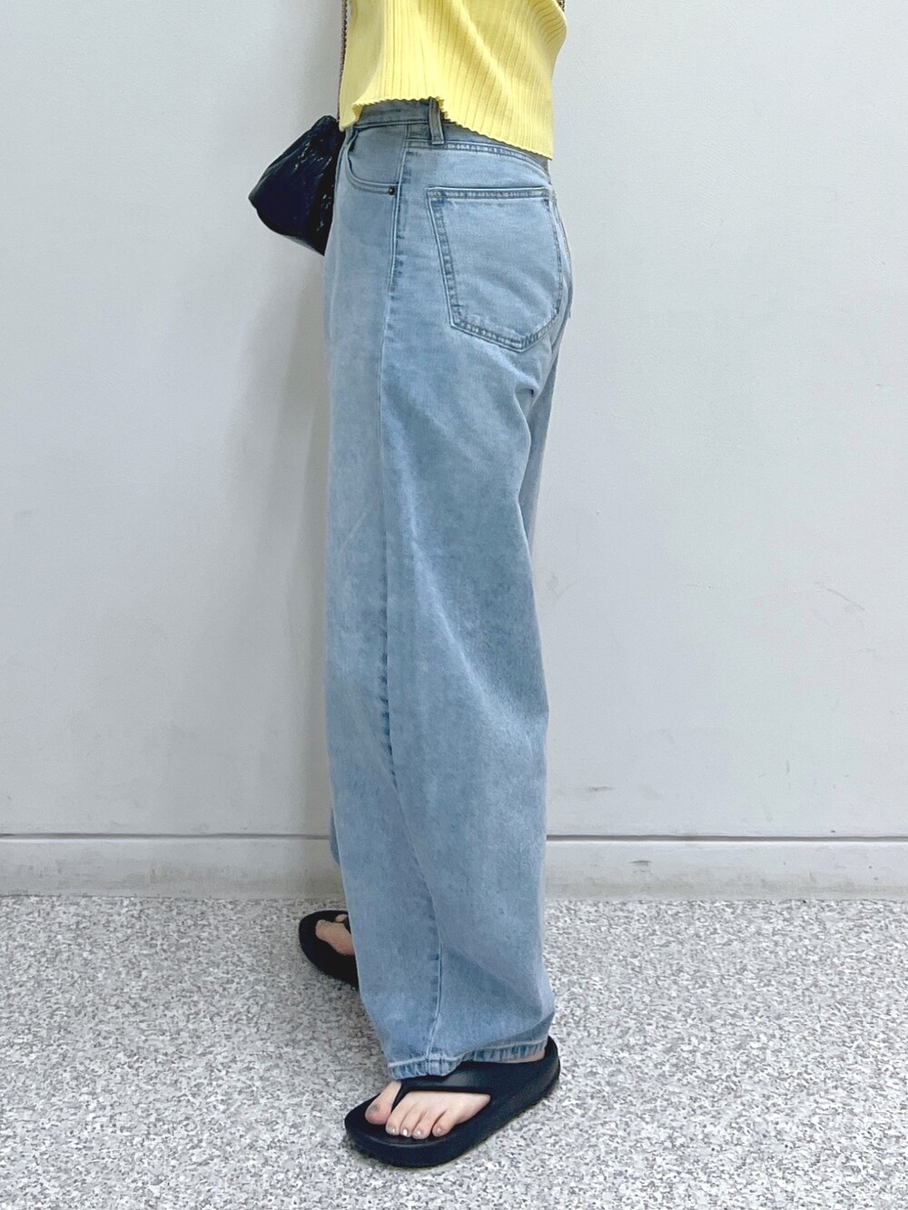 ブルー系のデニムパンツ、ブラック系のショルダーバッグ、イエロー系のニット/セーターを着用したレディースの夏コーディネートの6枚目の写真