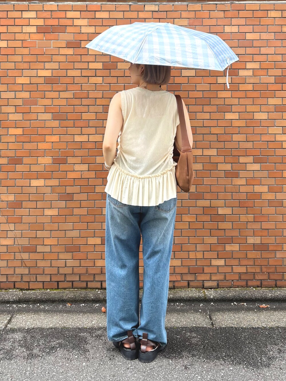 イエロー系のTシャツ/カットソー、ブルー系のデニムパンツ、ブラウン系のサンダルを着用したレディースの夏コーディネートの3枚目の写真